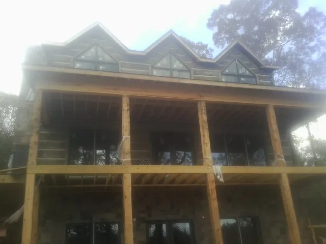 Dormers and porch framing on a large log home under construction — Roof Coating work by our crew in Platte City