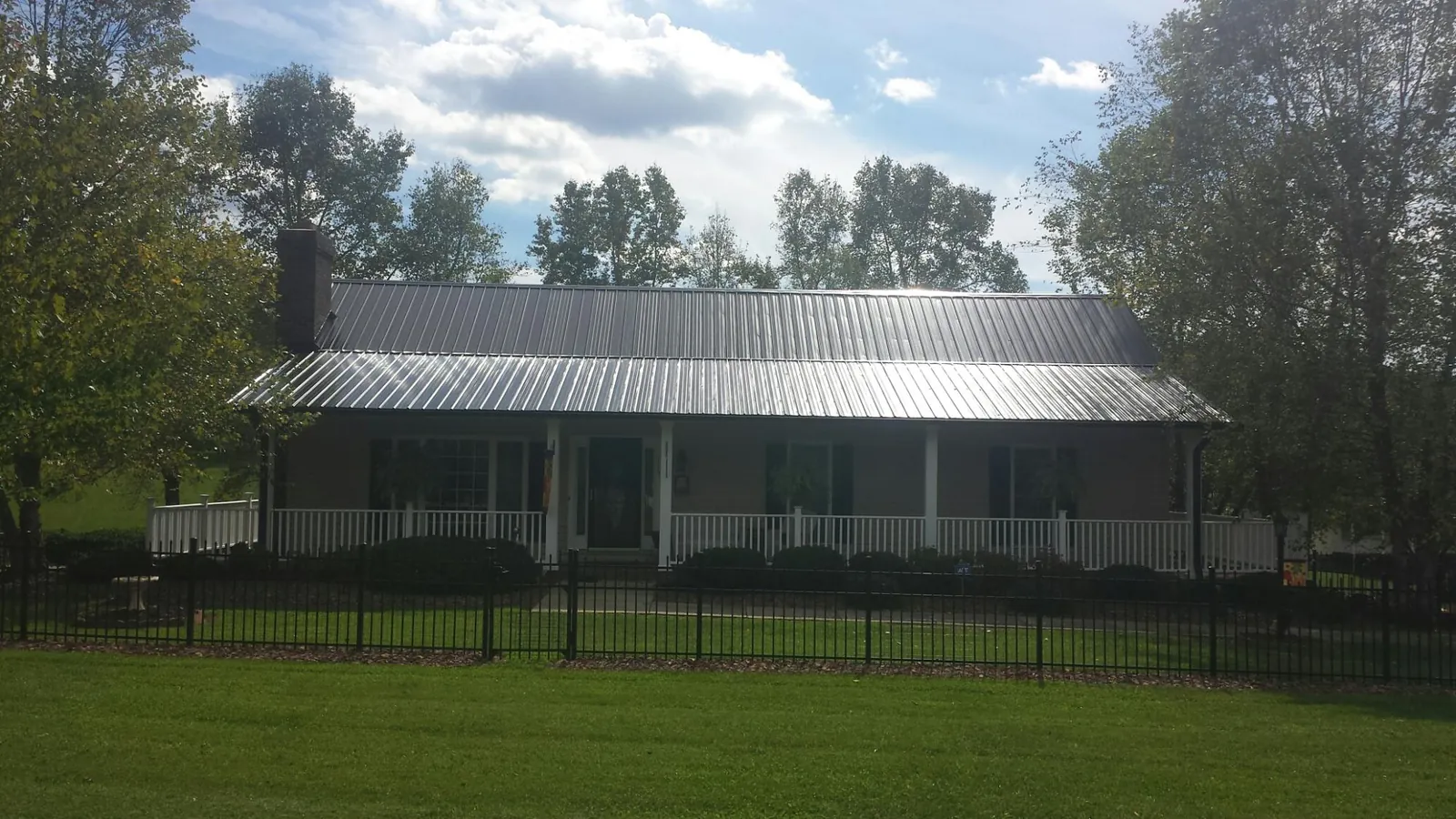 Gray metal roof on a brick ranch with a full width front porch — Gutter Guard Installation work by our crew in Platte City