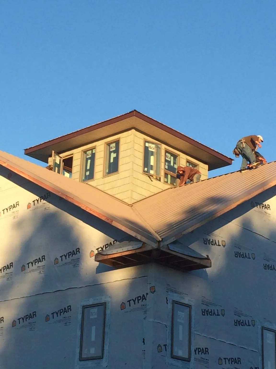 Roofers working around a rooftop cupola on a new metal roof at sunset — Roof Waterproofing in Platte City by Roofing Brothers